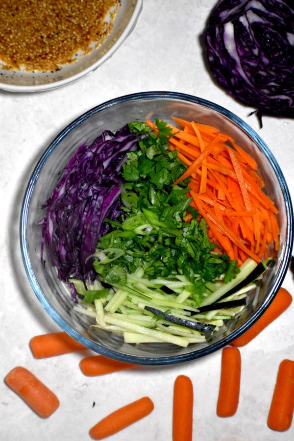 将胡萝卜、黄瓜和紫甘蓝切成薄片放入一个透明的碗中。