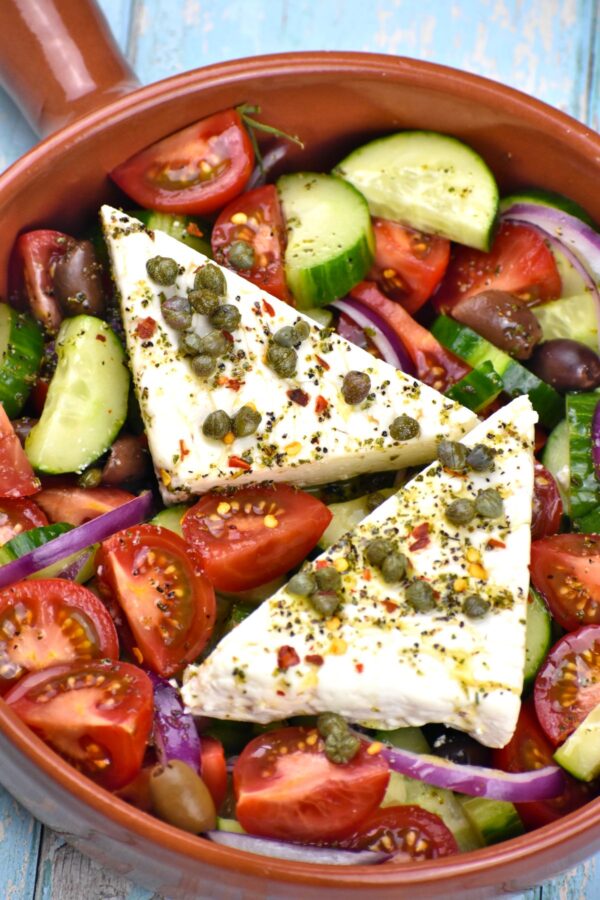 这真实的希腊沙拉食谱,当地称为Horiatiki,特征与咸乳酪,粗切蔬菜咸酸豆和橄榄,伟大的自制酱。