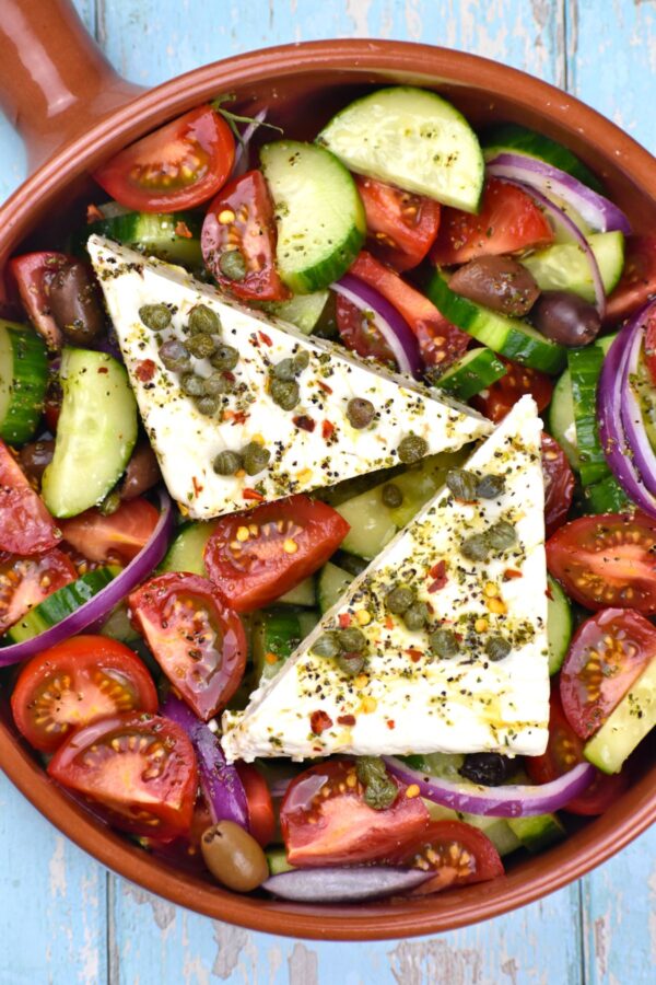 这真实的希腊沙拉食谱,当地称为Horiatiki,特征与咸乳酪,粗切蔬菜咸酸豆和橄榄,伟大的自制酱。