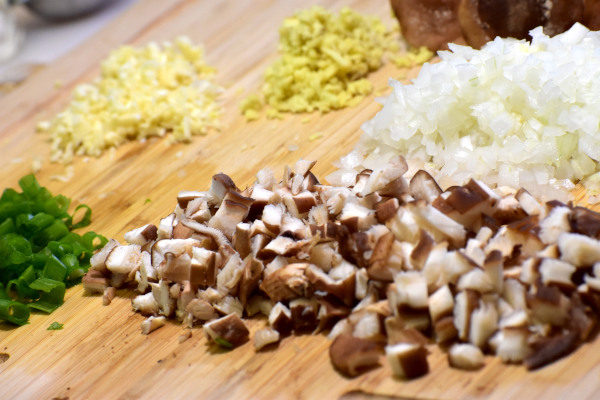 将香菇、葱、姜、蒜和大葱切碎，放在竹砧板上