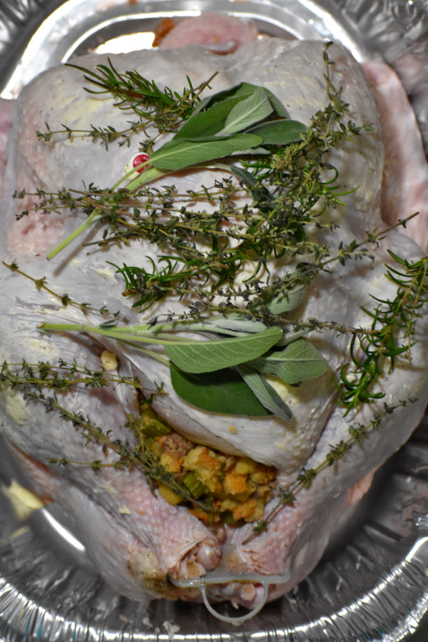 在铝锅中填充生火鸡，上面有新鲜的百里香，鼠尾草和迷迭香