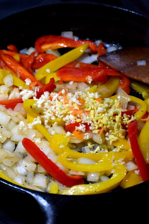 将洋葱、辣椒、大蒜和姜放入铸铁煎锅中
