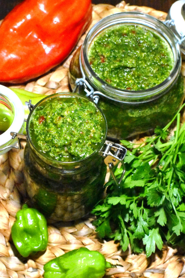 头顶的镜头是两个装满绿色调味料的玻璃瓶，周围是辣椒和香草。