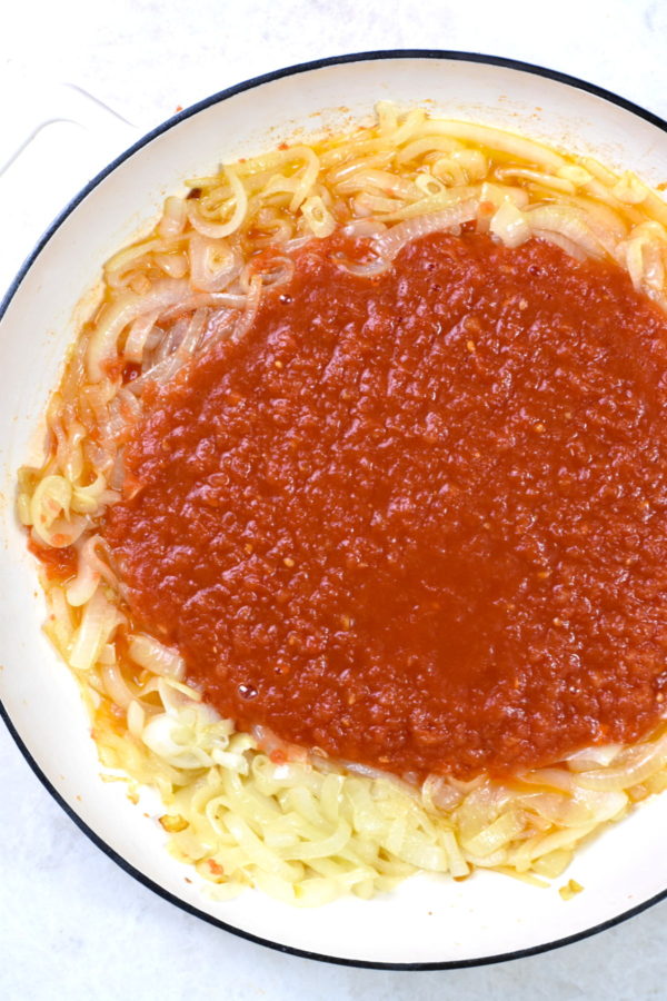 把番茄酱加在煮好的洋葱上，放在白色的炖锅里。