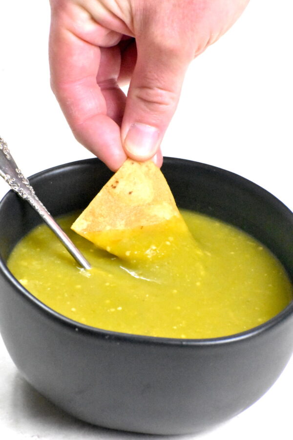 用手蘸着墨西哥玉米片蘸着绿辣酱。
