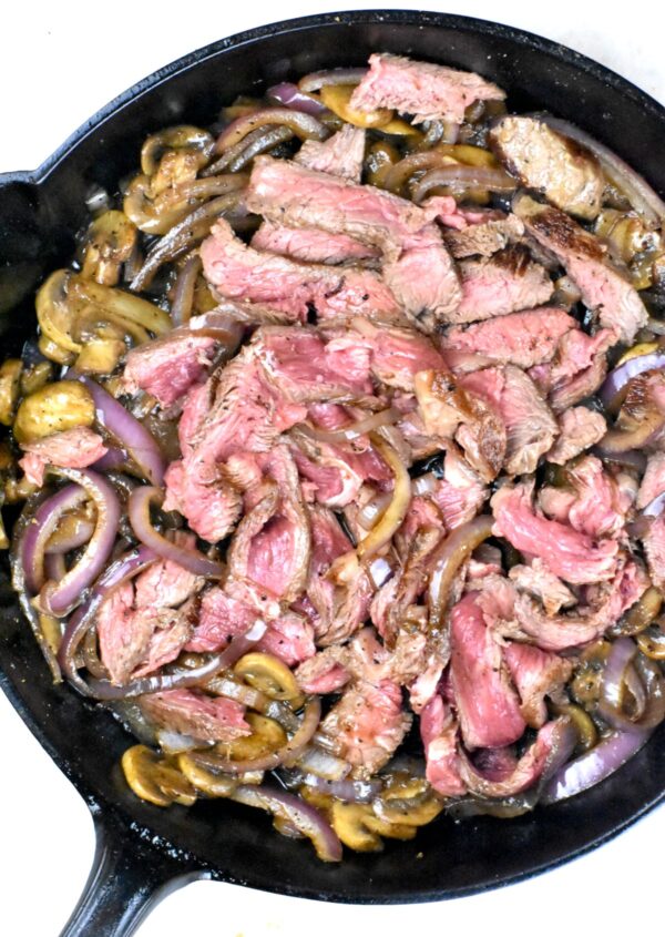 牛排和蔬菜的混合物在铸铁煎锅里